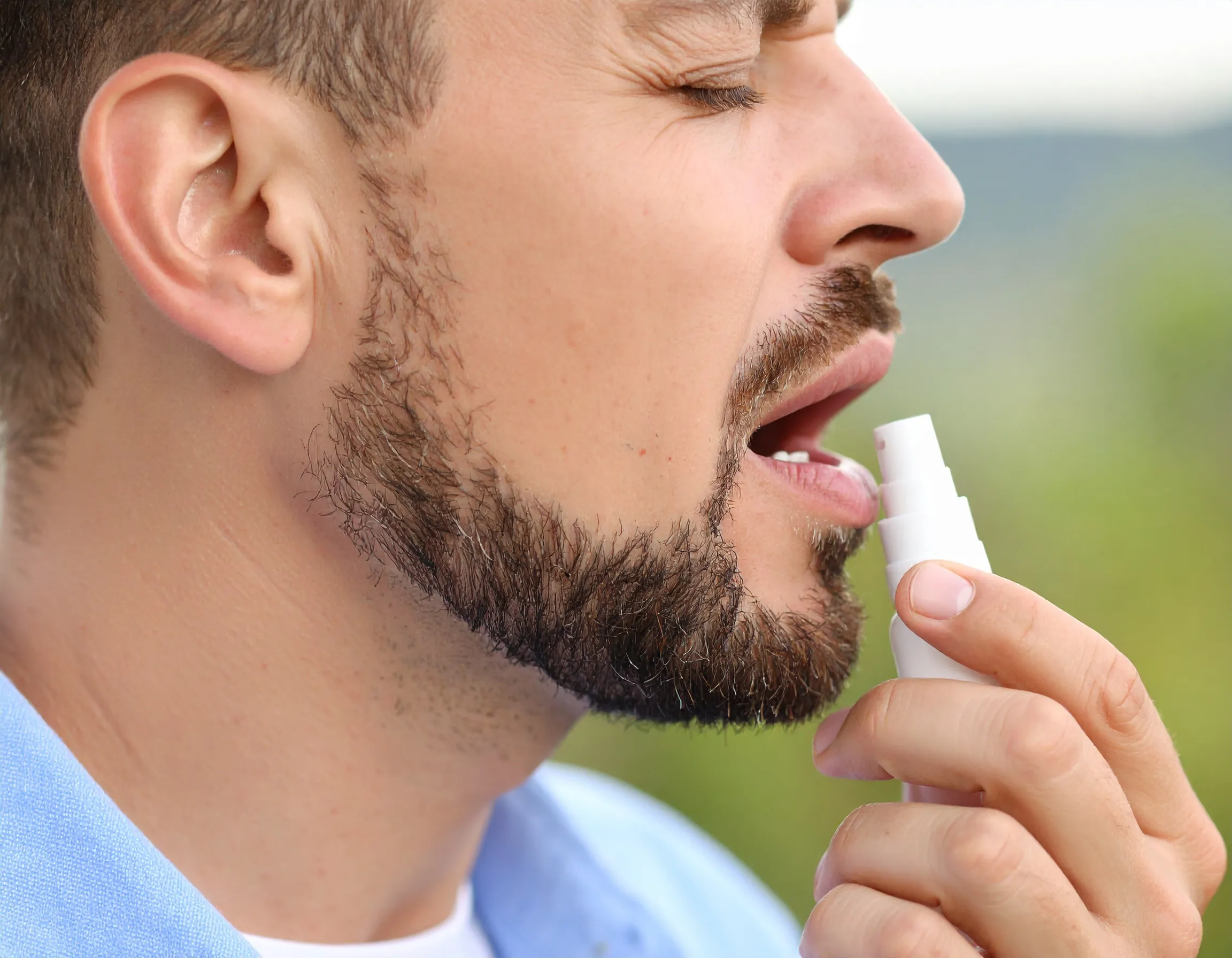 Man som använder en spray i munnen för att tillfälligt maskera dålig andedräkt.