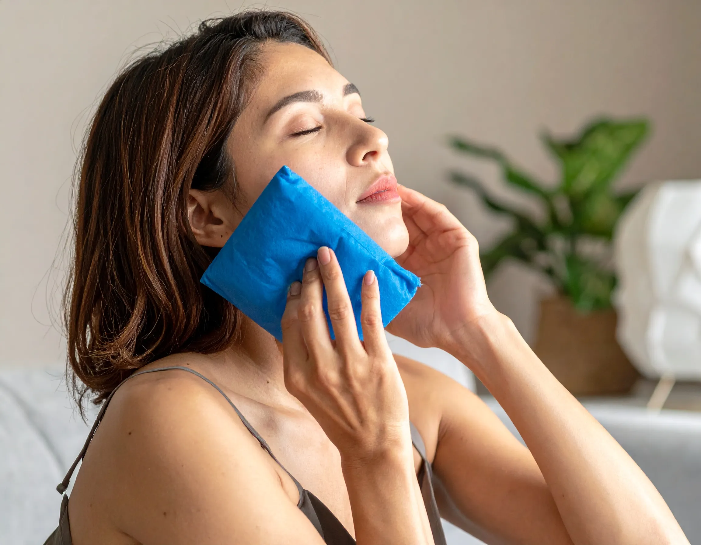 En person som vilar hemma med en kylklamp mot kinden efter en tandutdragning.