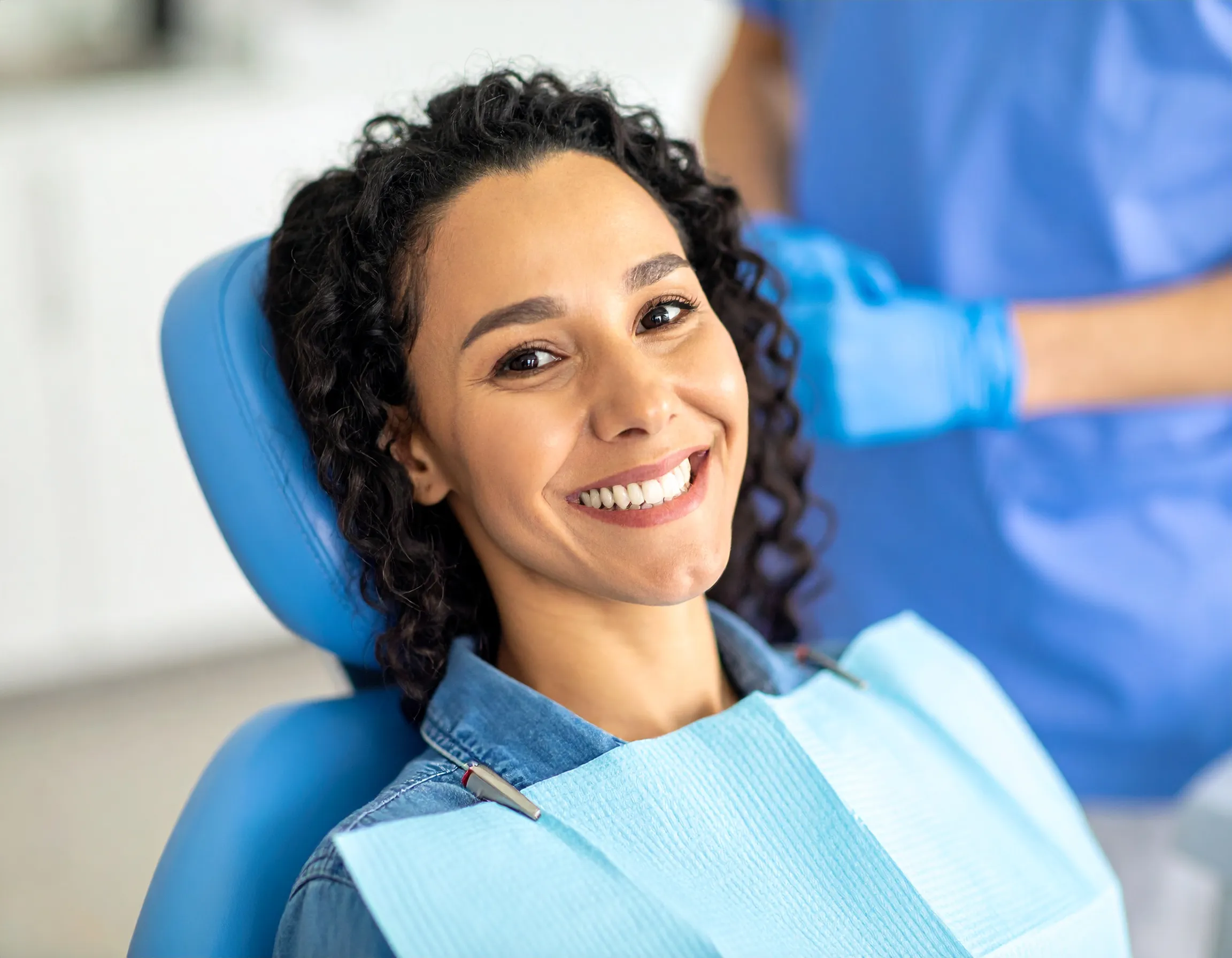 En glad patient som sitter i behandlingsstolen hos tandläkaren.